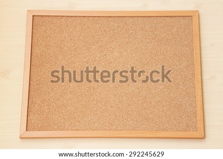 Blank Cork board with wooden frame on wooden floor.