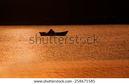 Silhouettes of a man and woman in the boat on the lake. Sunset. Light and shadow. Romance background.