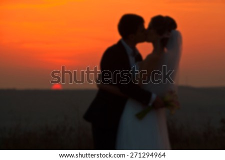 blurry wedding couple in love back light silhouette on sea at the sunset time
