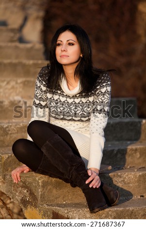 Autumn/winter portrait: young woman dressed in a warm woolen sweater in a city park