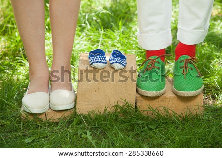 Mother and father waiting for a baby. New parents with shoes and baby shoes next to them.