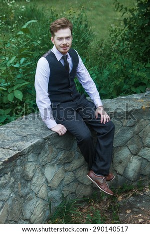 Elegant young handsome man in classic costume in city park.Fashion portrait of young  man in classic costume.Business men in class costume