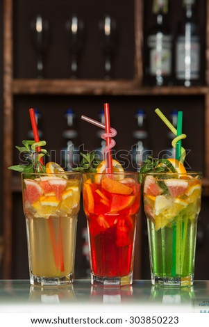 Fresh juice mix.Fresh citrus juice. Three orange summer cocktails with exotic fruit on bar.Glasses of orange.