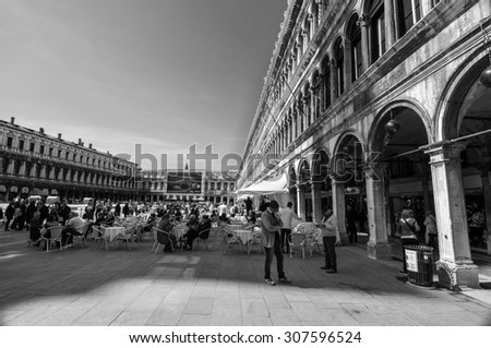VENICE, ITALY - APRIL 13, 2013: People visit San Marco square in Venice. Millions of tourists visit Venice. It is the most romantic italian city. Black and white photography.