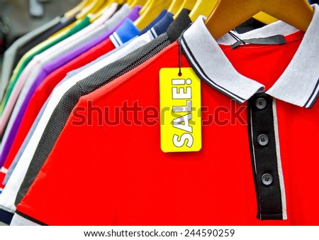 man shirts. man shirts on hangers with sale tag. focus on red shirt.