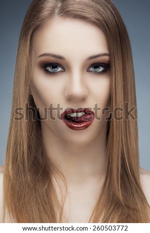 Beauty fashion female vampire fangs at the camera with fancy make-up