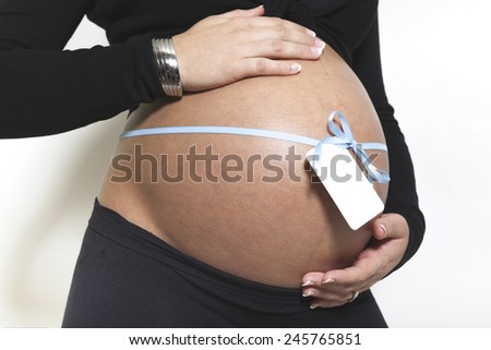 Belly of a pregnant woman with a white tag where to write a name
