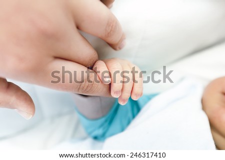 A baby\'s hand holding the finger of his dad or his mom