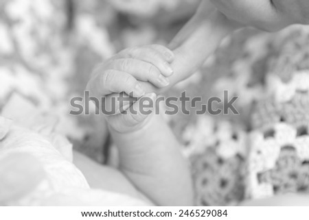 Black and white photo of a baby\'s hand holding the finger of his dad or his mom
