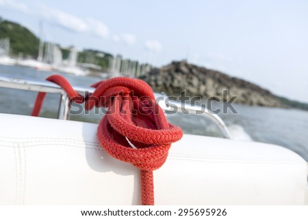 Soft focus of mooring red rope tied around steel anchor on boat