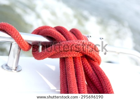 Soft focus of mooring red rope tied around steel anchor on boat with. Shallow depth of field