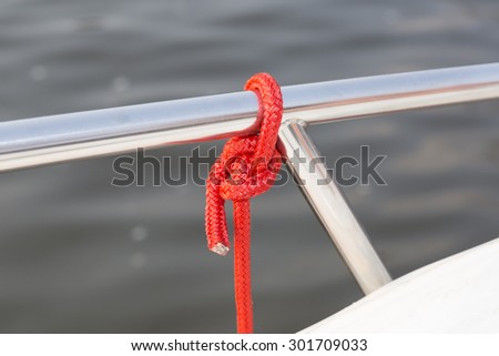 Closeup of red mooring rope tied around steel anchor on boat or ship. Red mooring rope on ship