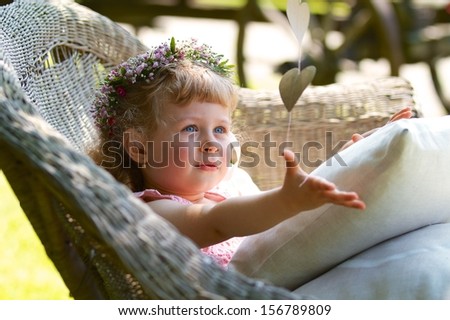 Three years old bridesmaid girl with wreath on the head catching paper hearts