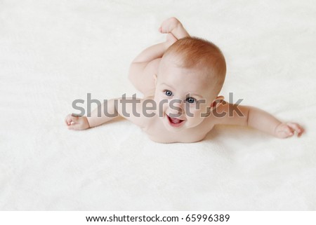 happy small baby lying on the belly and smiling - in the move