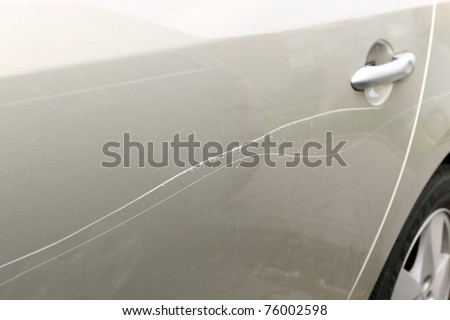 Scratched car paint with door handle and tire out of focus