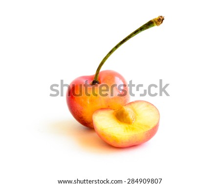 A single Rainier and a slice cherry on white background. They are grown in Yakima Valley, a prime agricultural area of Washington State and the largest variety of crops in the Pacific Northwest.