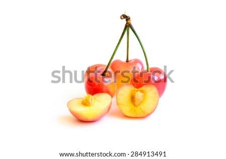 Three Rainier cherries and slices on white background. They are grown in Yakima Valley, a prime agricultural area of Washington State and the largest variety of crops in the Pacific Northwest.