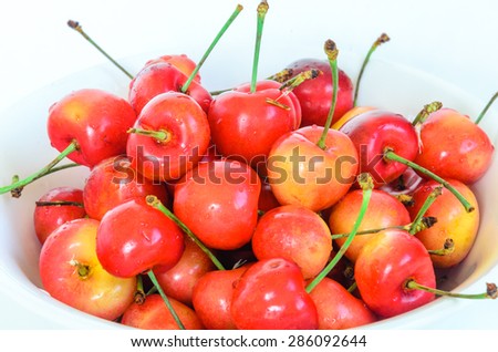A bowl of Rainier cherry on isolated white background. Rainiers are sweet cherries with a thin skin and thick creamy-yellow flesh.