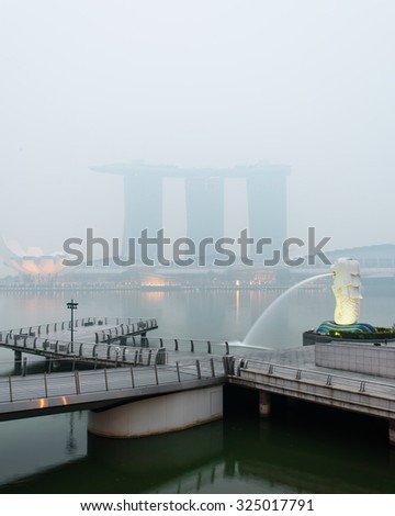 SINGAPORE-SEP 24, 2015: Haze fills the Marina Bay area. Haze is caused by the forest fire and burning of plantation in Indonesia. Also visible is the Merlion statue and Marina Bay Sands luxury hotel