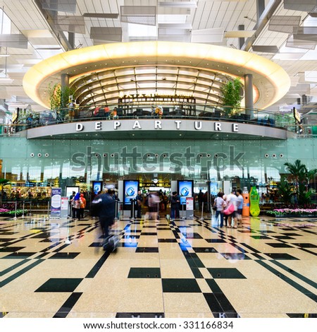 SINGAPORE - OCT 10, 2015: Visitors walk toward Departure Hall in Changi Airport. It has three passenger terminals, and is one of the largest transportation hubs in Asia with 66 mil passengers per year