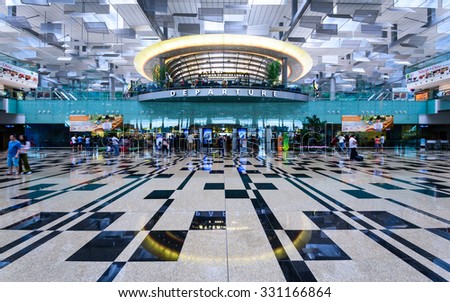 SINGAPORE - OCT 10, 2015: Visitors walk toward Departure Hall in Changi Airport. It has three passenger terminals, and is one of the largest transportation hubs in Asia with 66 mil passengers per year