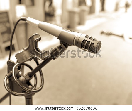 Close-up of a standing microphone in a street music performance/show in city. Abstract musical instrument background on a street concert. Vintage look