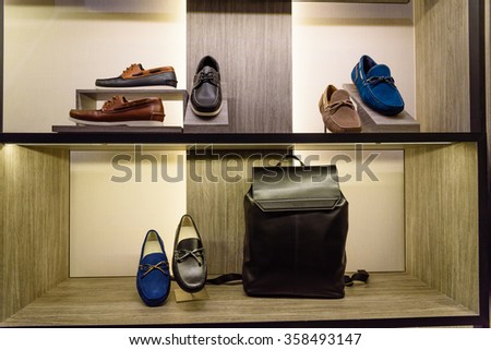 Variety colorful leather casual derby, slip-ons (or drivers) shoes and business handbag on the shelf in the menâ??s fashion footwear and accessories shop. Business and executive, self-grooming concept.