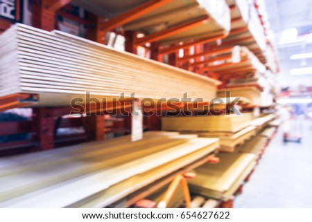 Blurred wooden bars from floor to ceiling at lumber yard of hardware store in America. Rack of pre-cut panel, mill wood timber, red oak, poplar, cedar, whitewood board, siding, plywood on flatbed cart