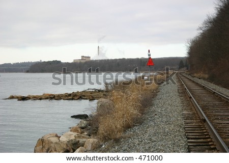 Industrial scene with railroad tracks and smoke stack,
