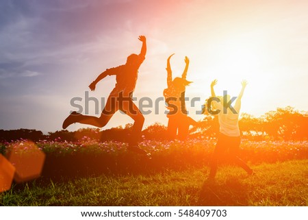 Silhouette of happy people jumping in sunset.