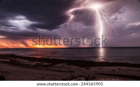 Lightening storm moving in over beach at sunset.