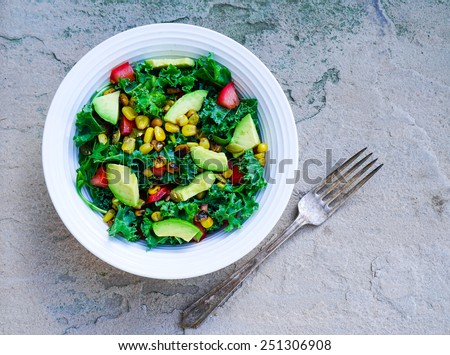 Kale, corn and avocado salad on rustic stone background