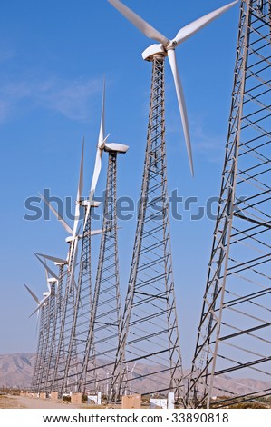 vertical of a row of wind turbines against a blue sky