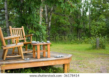 two pine log chairs on porch with stacks of gathered rocks