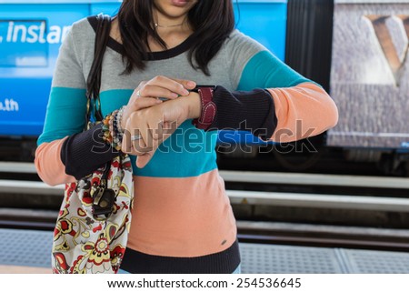 woman looking at her smart watch on electrical sky train at station