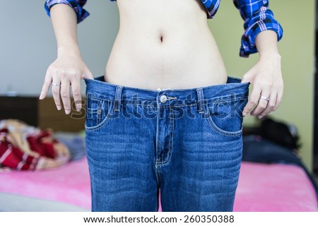 Woman shows her weight loss by wearing an jeans