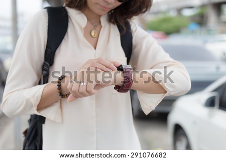 A female(woman) looking at her smart watch, background car park.