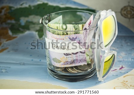 Travel budget money savings in a glass jar on world map