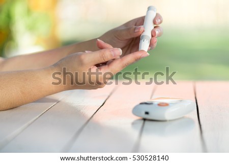 close up of asian woman hands using lancet on finger to check blood sugar level by Glucose meter, Healthcare Medical and Check up, Medicine, diabetes, glycemia, health care and people concept