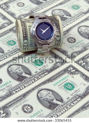 Wrist watch with a money roll on a background of two dollar bills.