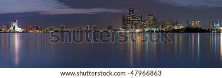 XXL Panoramic of the Detroit Windsor skyline with the Ambassador Bridge connecting the United States with Canada.  Night shot with city lights reflecting in the Detroit River.