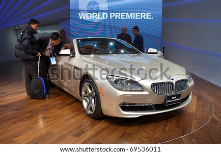 DETROIT - JANUARY 11: Members of the press look at the new BMW 650i convertible on display at the 2011 North American International Auto Show Press Preview on January 11, 2011 in Detroit, Michigan.