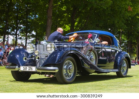 PLYMOUTH - JULY 26: A judge places an award ribbon a vintage Mecedes July 26, 2015 at the Councors D\'Elegance in Plymouth, Michigan.