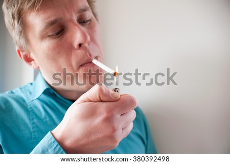 Young blonde man lighting cigarette