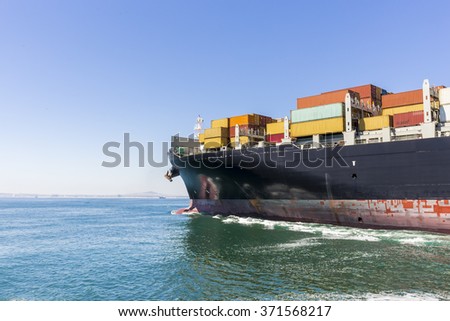 Cargo ship loaded with containers sailing away.
