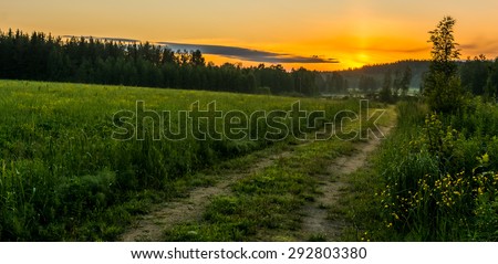 Country road leading to sunset over the mountains in summer night in Finland