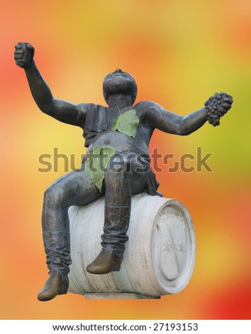 Metal sculpture of wine drinking man sitting on barrel with colorful blurry background