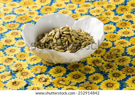 Sunflower kernels in a white bowl on the bright sunflower tablecloth