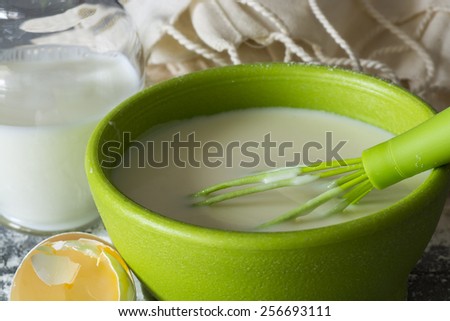Pancake batter mix in a green bowl on the wood background.