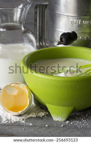 Pancake batter mix in a green bowl on the wood background.
